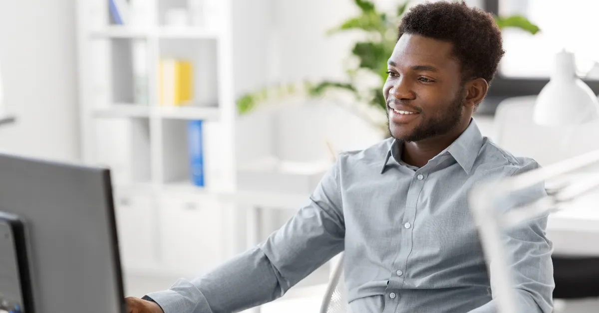 Smiling professional researching intranet software options at his office desk.