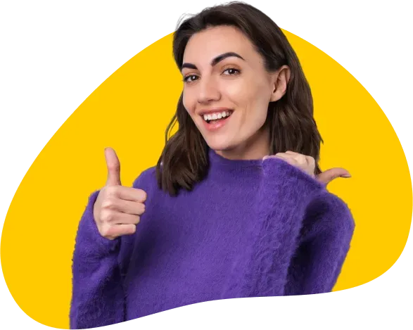 Smiling woman in purple sweater giving thumbs up against bright yellow background, cheerful and enthusiastic.
