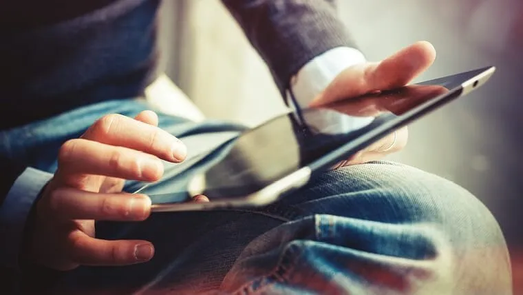 Close-up of a person in business attire using a smartphone while seated, focusing on their hands and the device.