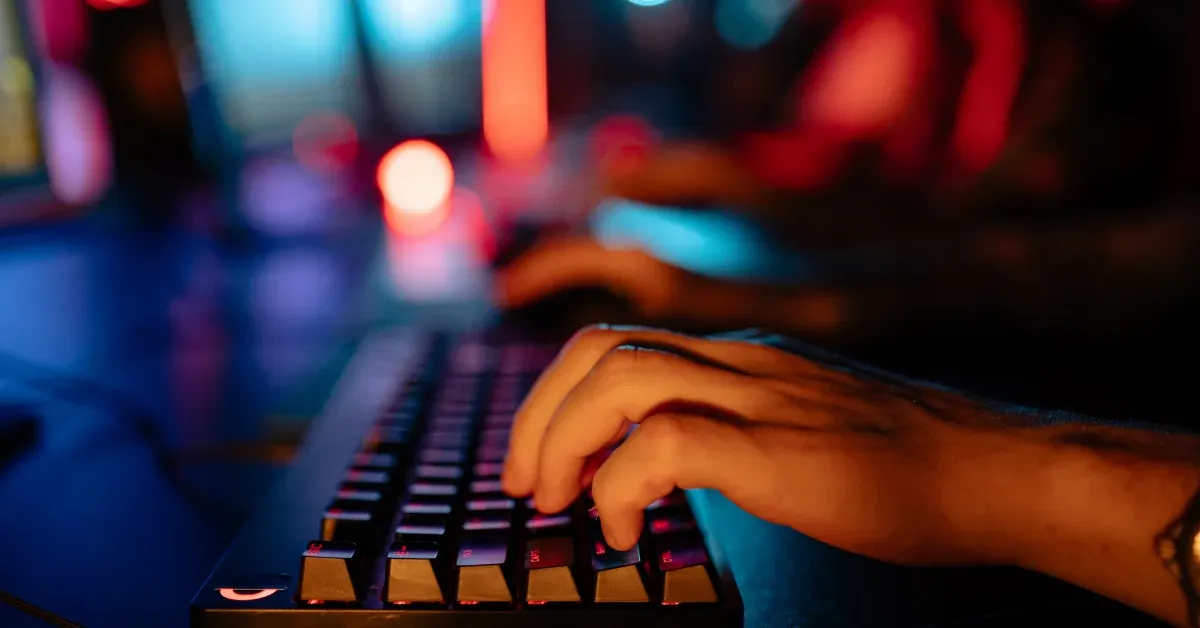 Close-up of hands typing on a backlit mechanical keyboard in a dim server room