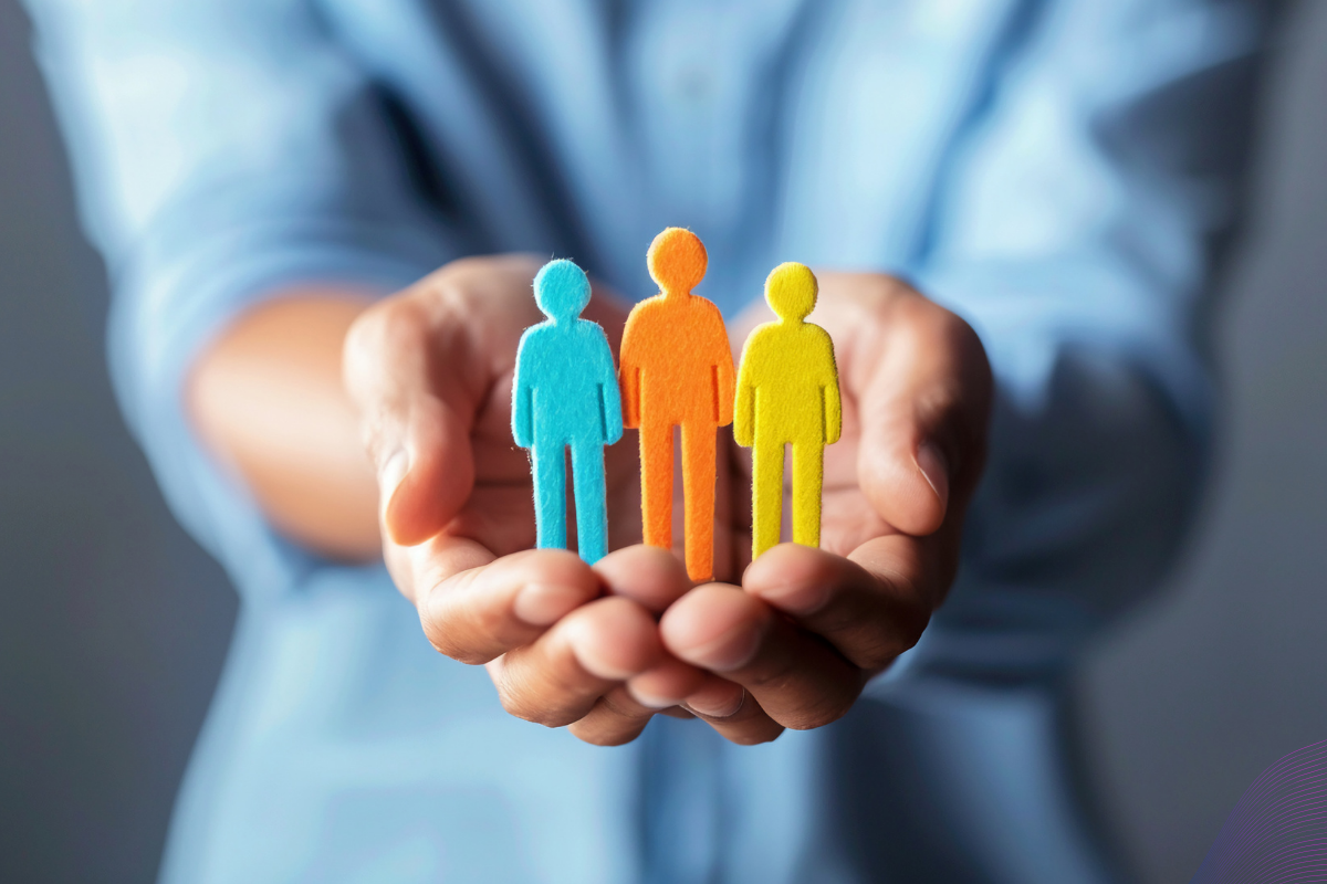 A person holding a chain of paper people cutouts, symbolizing how an employee handbook unifies an organization through consistent company policies and shared company values.